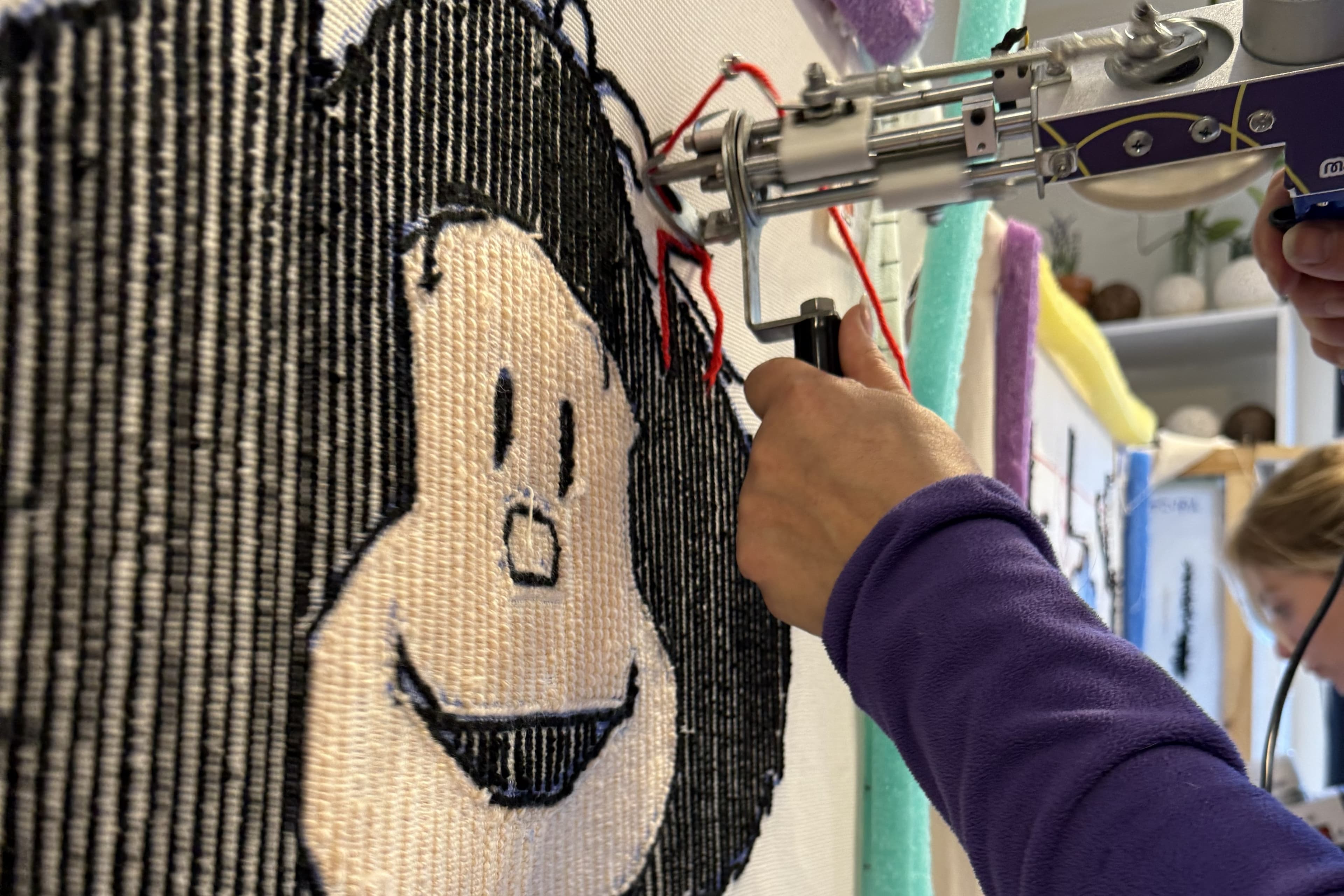 Persona usando pistola de tufting para crear un diseño de Mafalda en bastidor